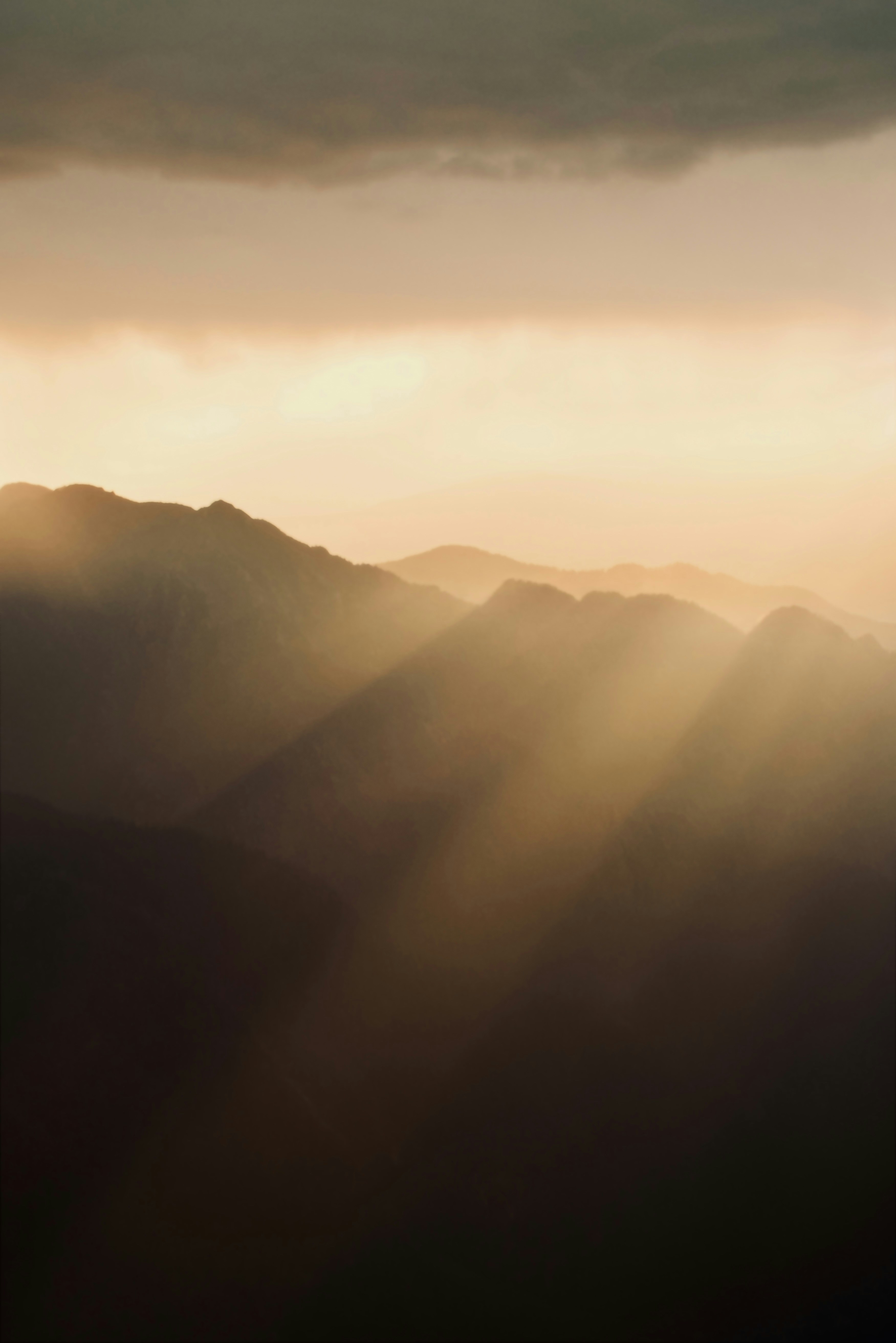 the sun is shining through the clouds over the mountains