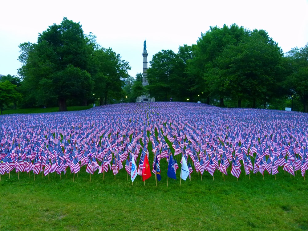 배경에 기념비가있는 미국 국기로 가득한 들판