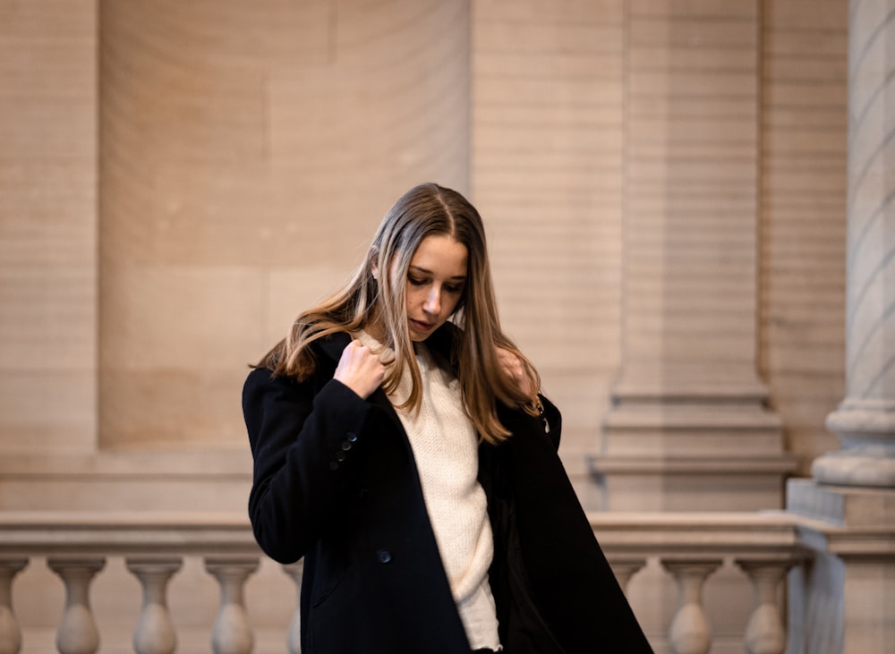 Eine Frau in schwarzem Mantel und weißem Pullover