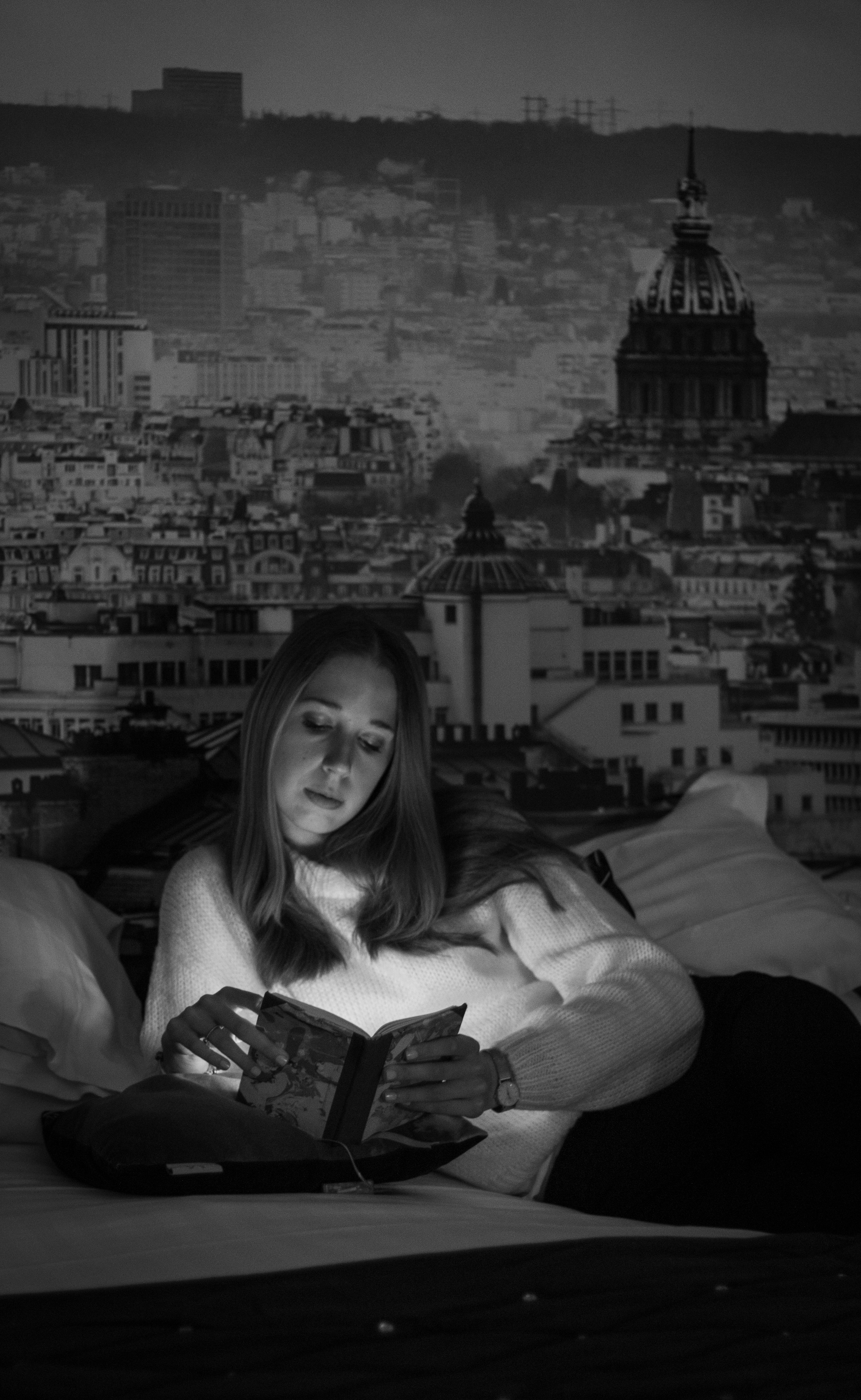 a woman sitting on a bed reading a book