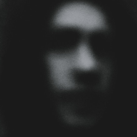 A dark, grainy close-up of a vintage horror movie poster with eerie shadows.