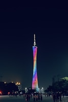 Dynamic tower lighting illuminating an outdoor event, casting vibrant colors over a lively crowd.