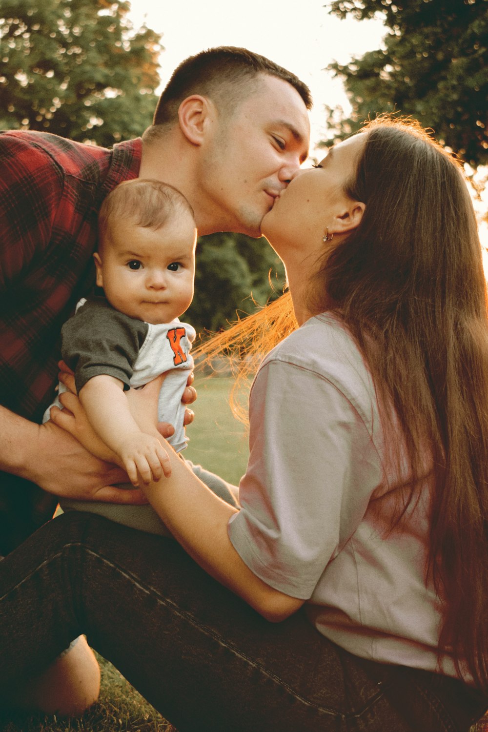 a man kissing a woman while holding a baby