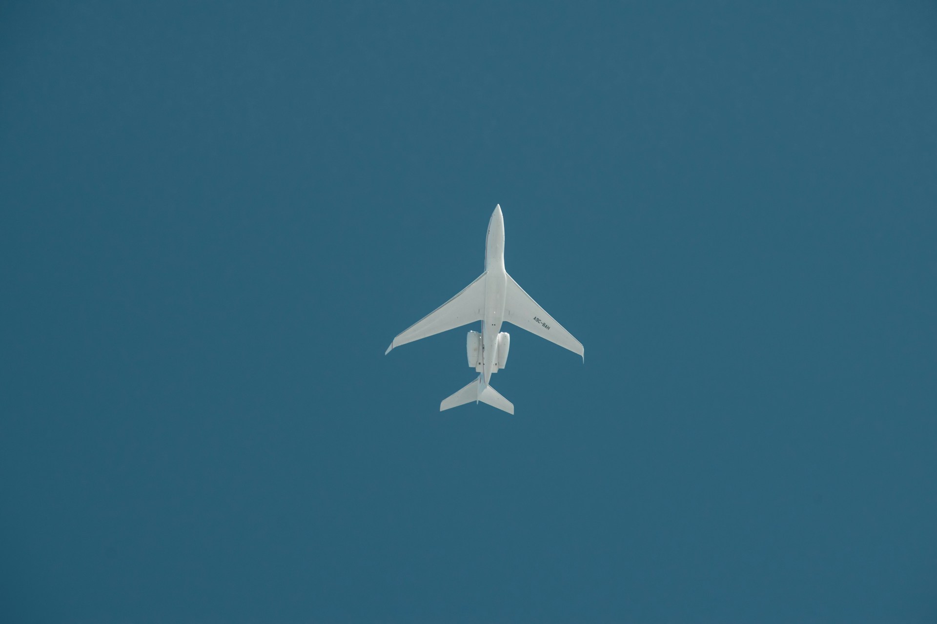 a white jet flying through a blue sky