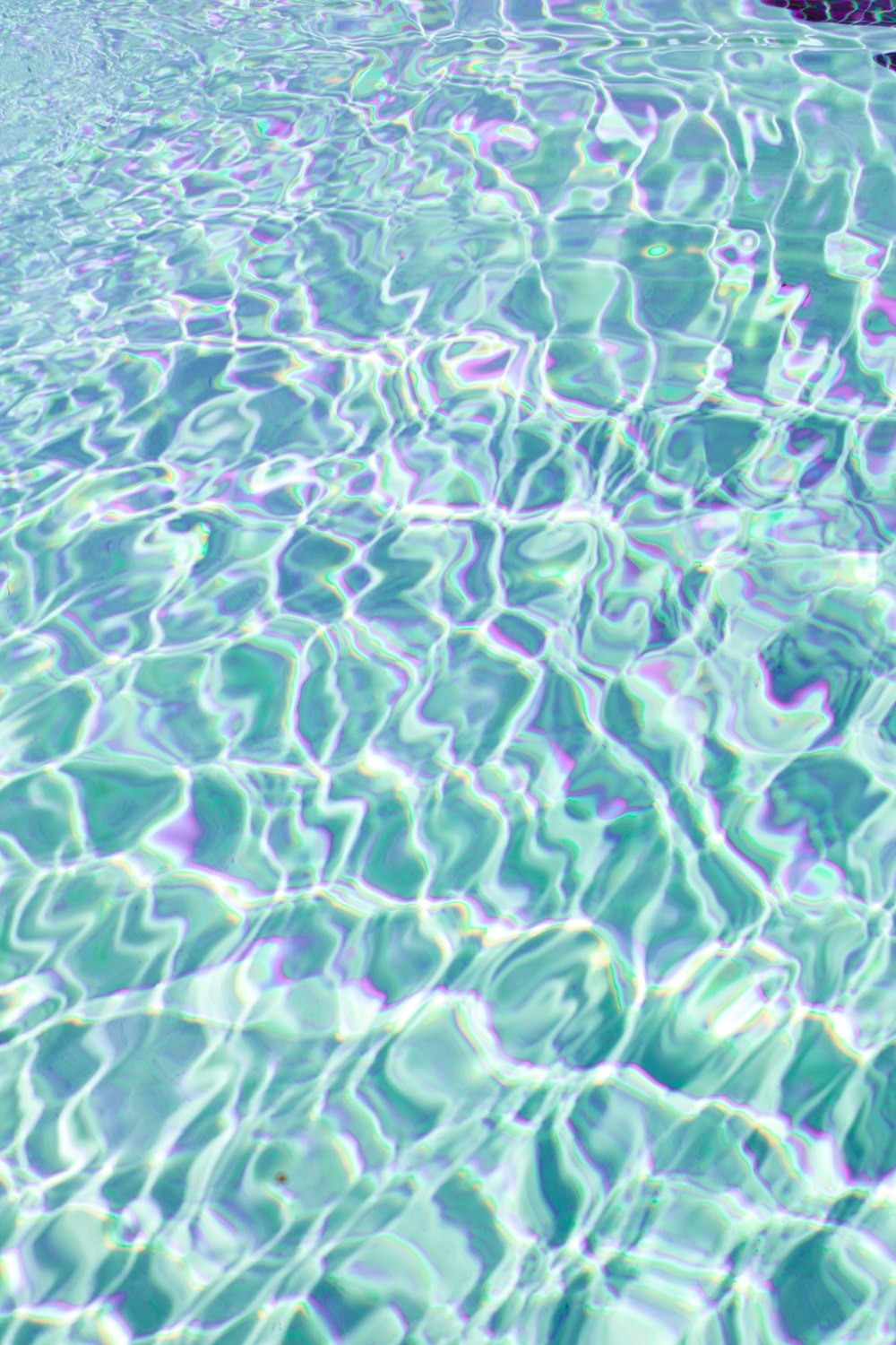 una piscina con agua azul clara y una roca en el medio