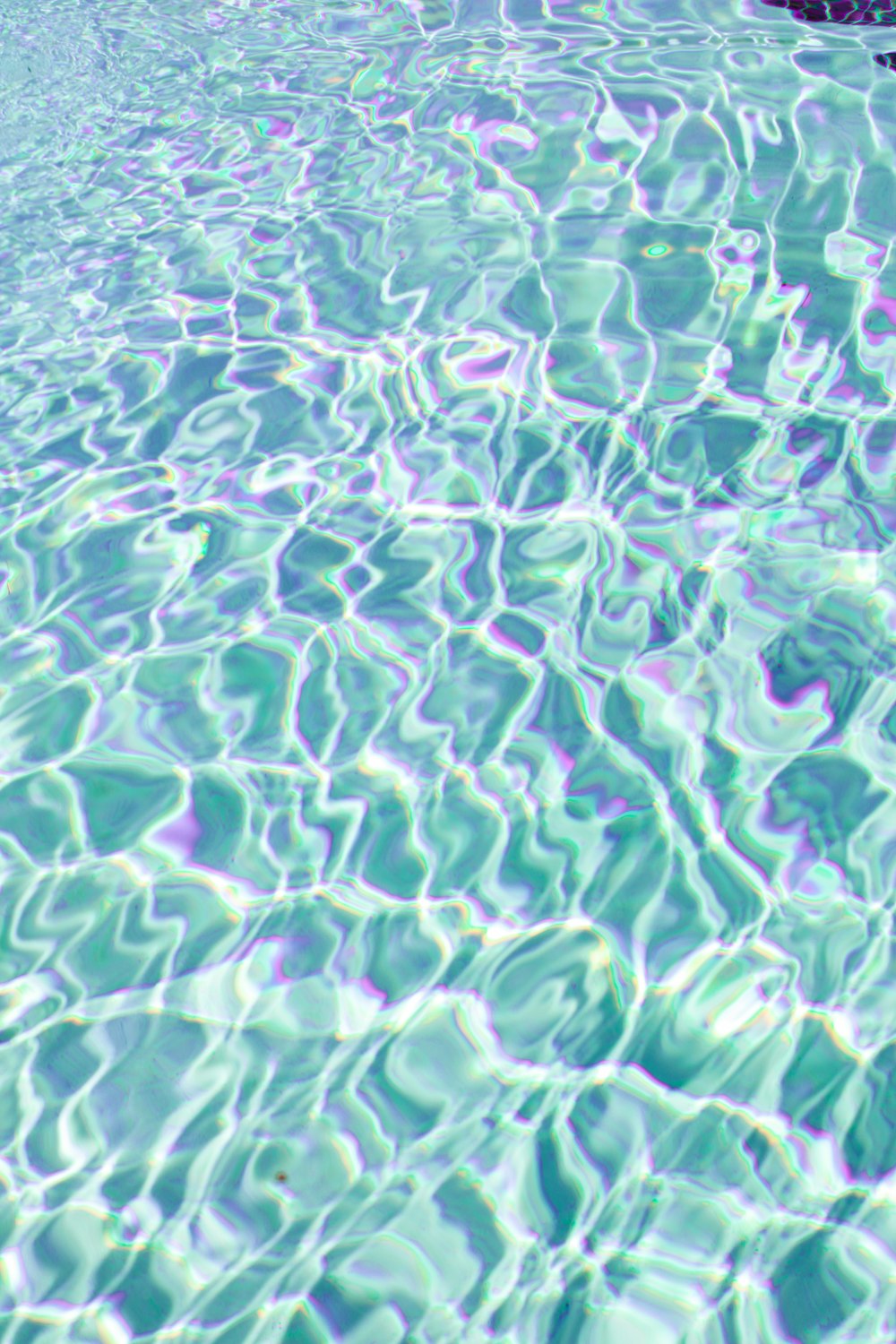 a pool with clear blue water and a rock in the middle