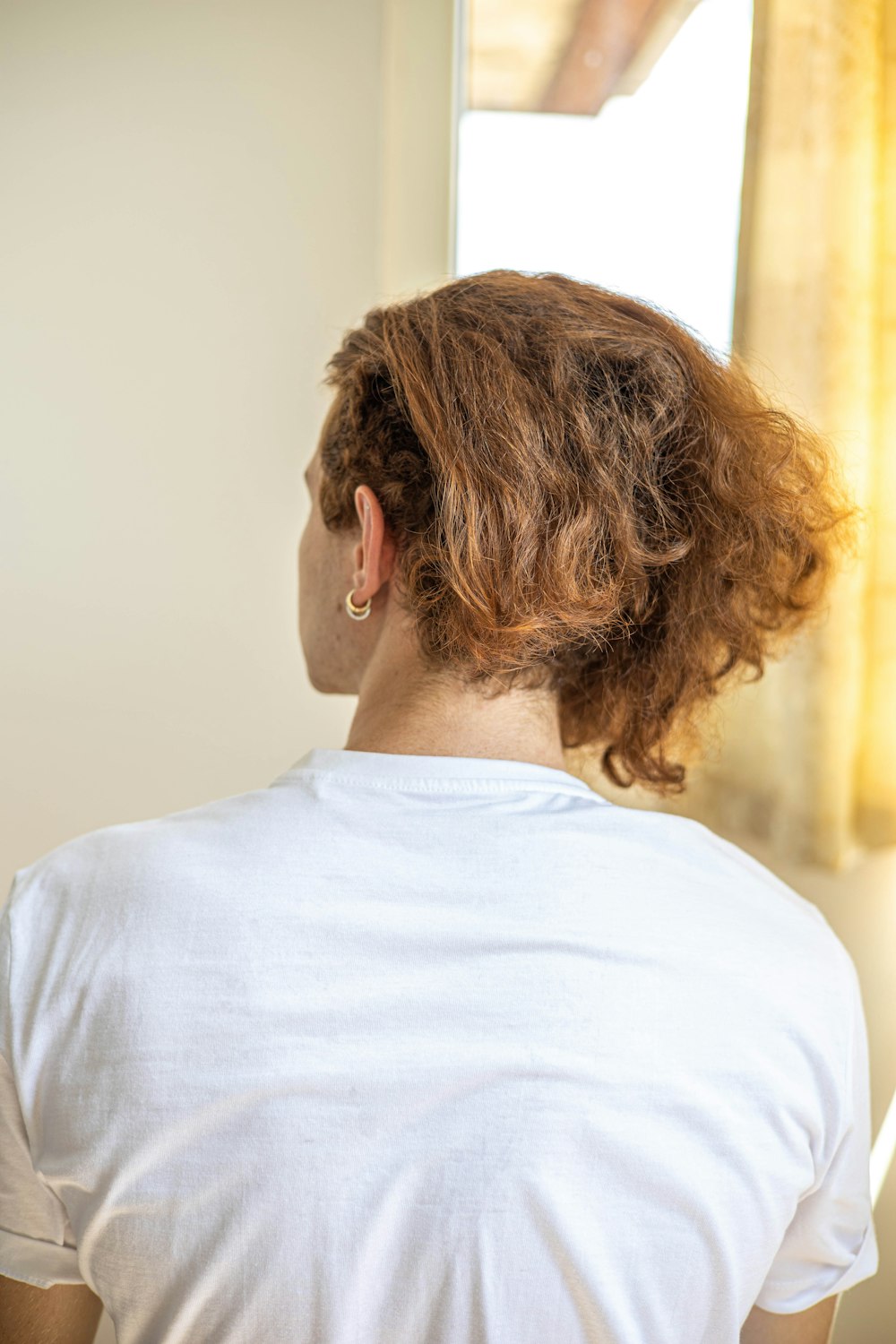 a woman in a white shirt looking out a window