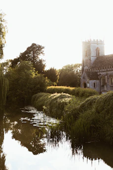 A serene view of Bramham Sanctum's ancient stone church bathed in soft morning light, surrounded by lush greenery.