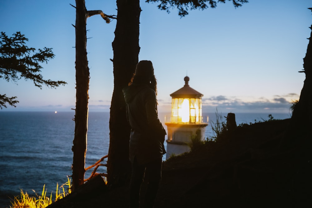 a woman standing in front of a light house