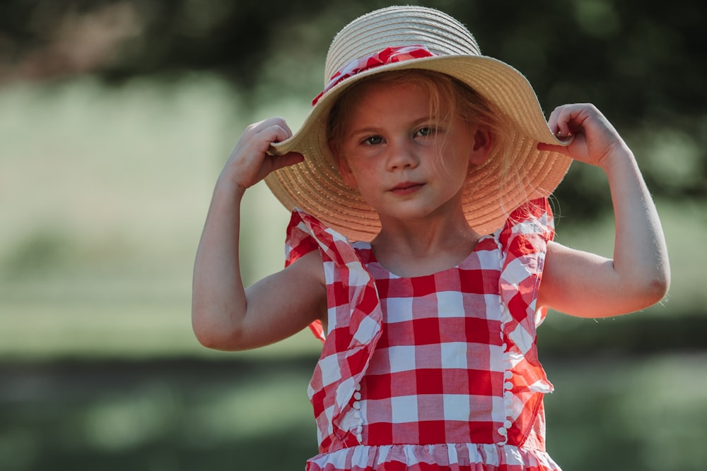 Foto Una niña con un vestido a cuadros rojo y blanco y un sombrero de paja  – Imagen Ropa gratis en Unsplash