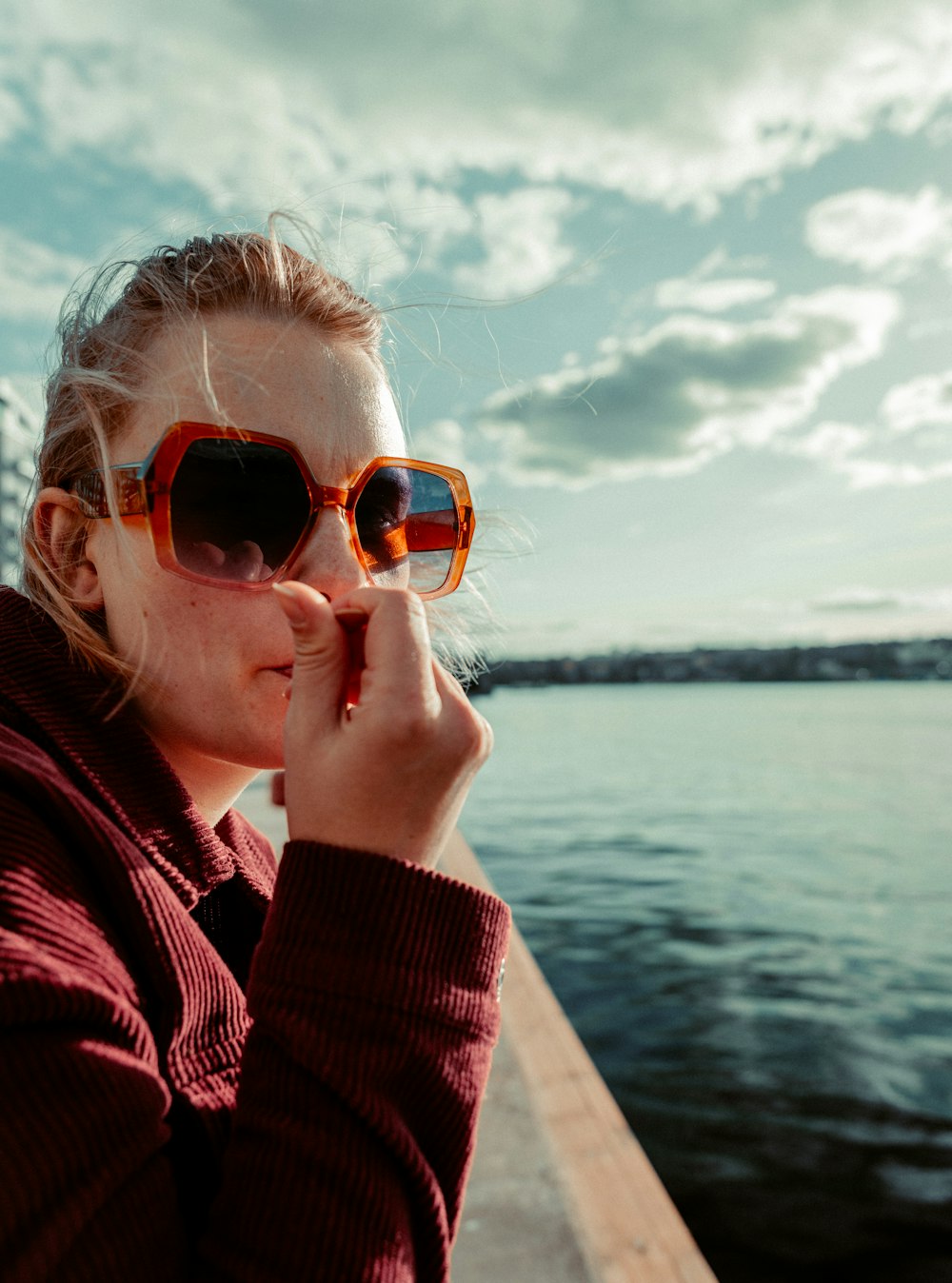 a woman wearing sunglasses looking out over a body of water