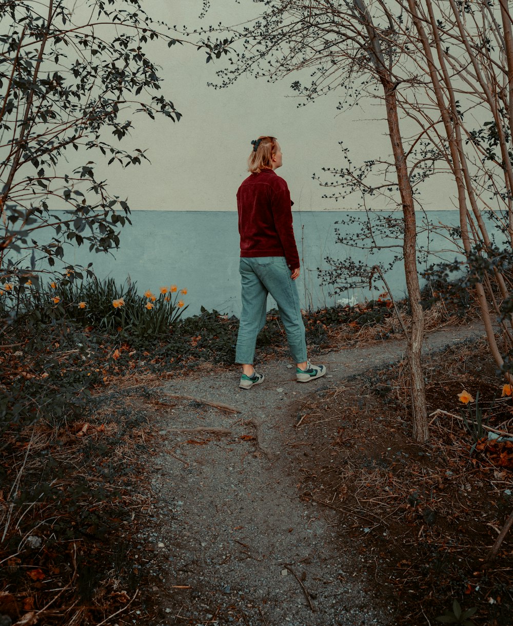 a woman walking down a path next to trees