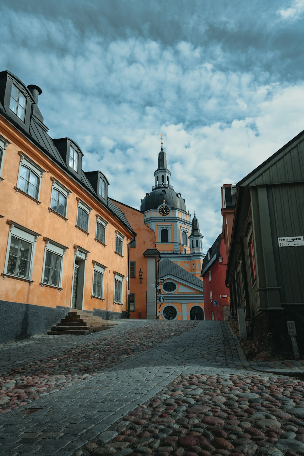 a cobblestone street with a church steeple in the background