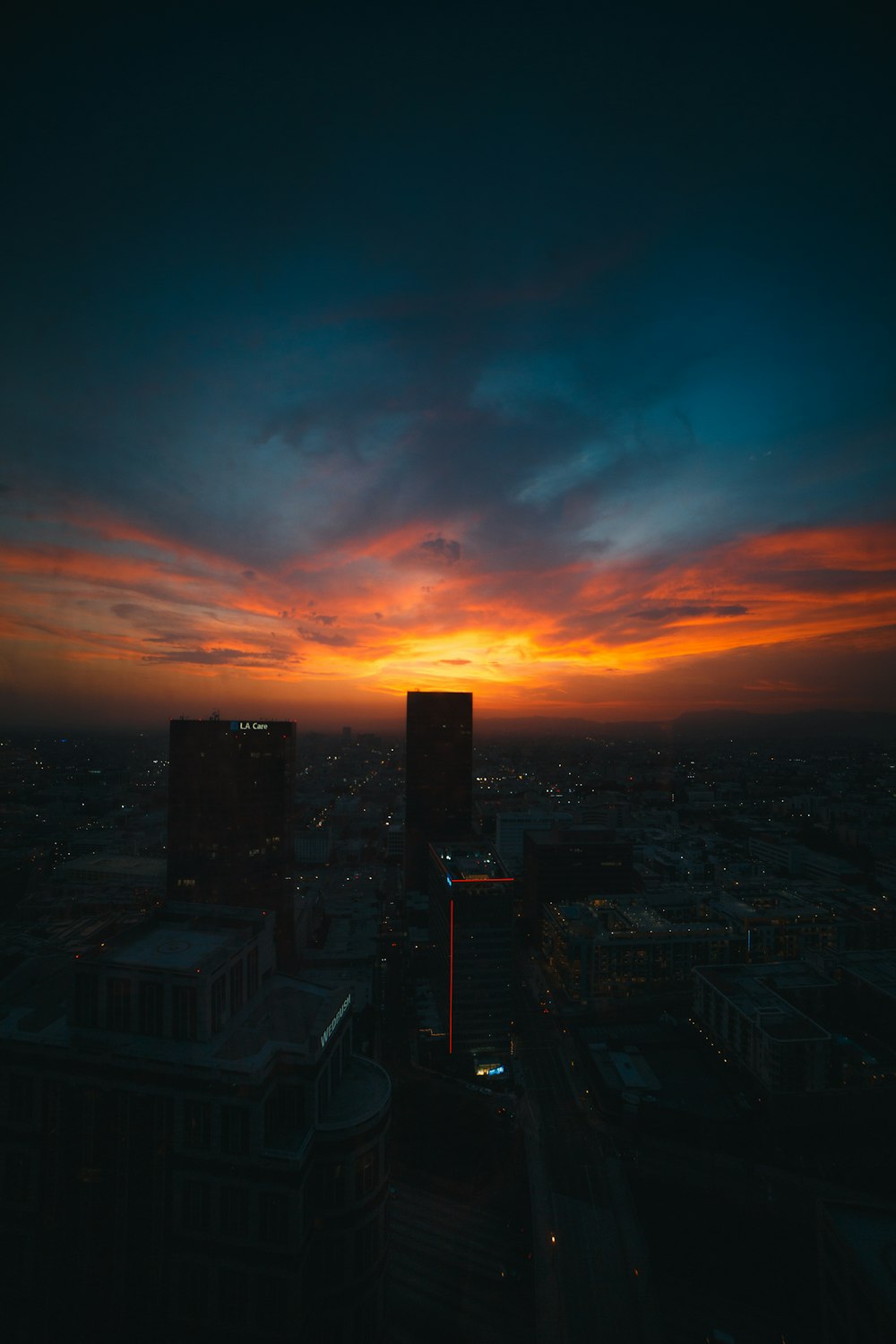 the sun is setting over a city with tall buildings