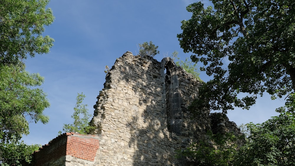 a stone building with a red roof surrounded by trees