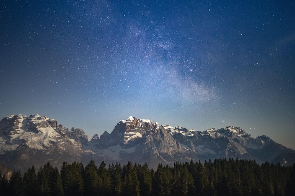 the night sky over a mountain range with stars in the sky