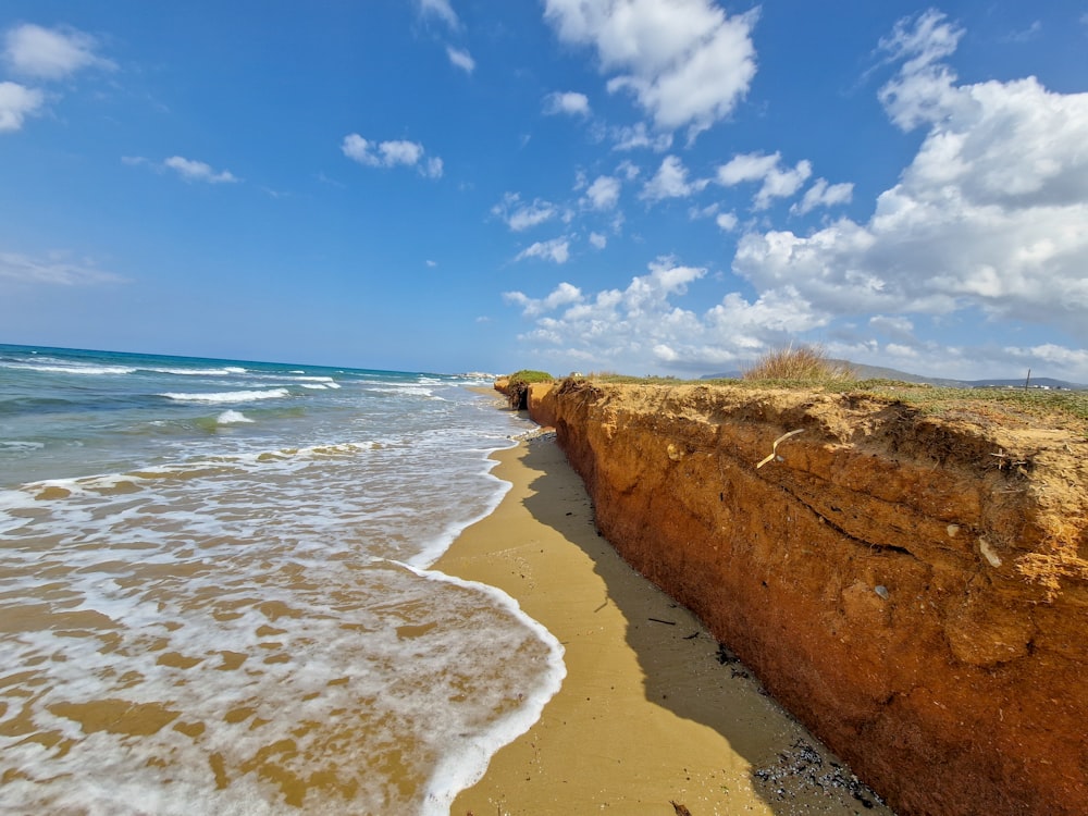 a sandy beach next to the ocean under a blue sky