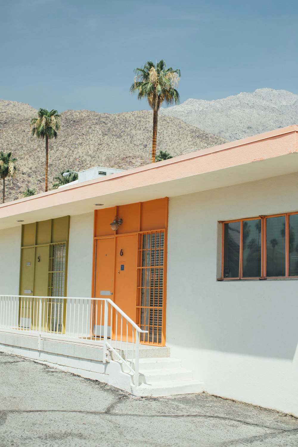 a white building with a yellow door and palm trees