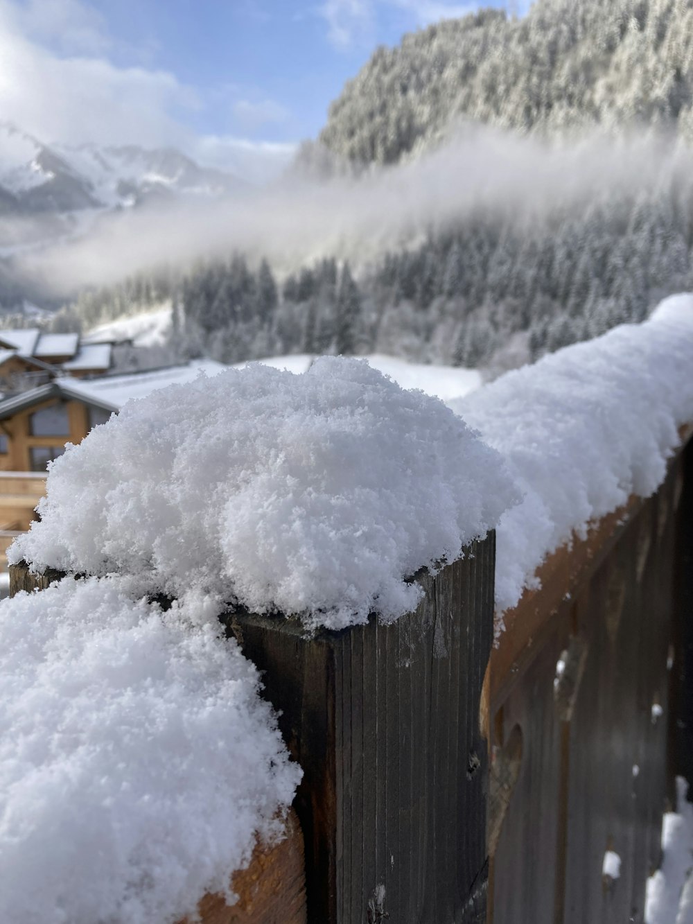 ein schneebedeckter Holzzaun neben einem Berg