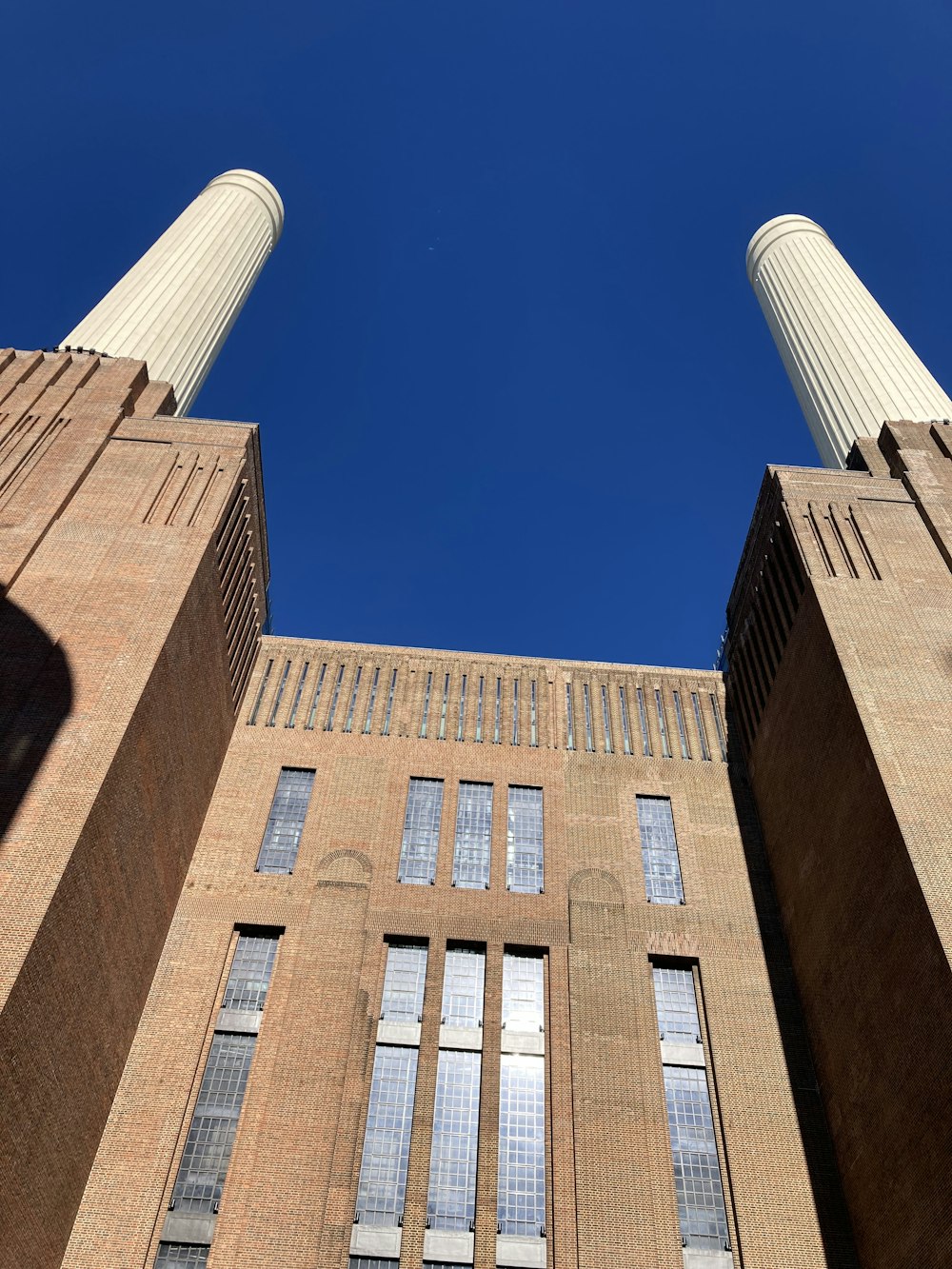 two tall brick buildings with windows and a sky background