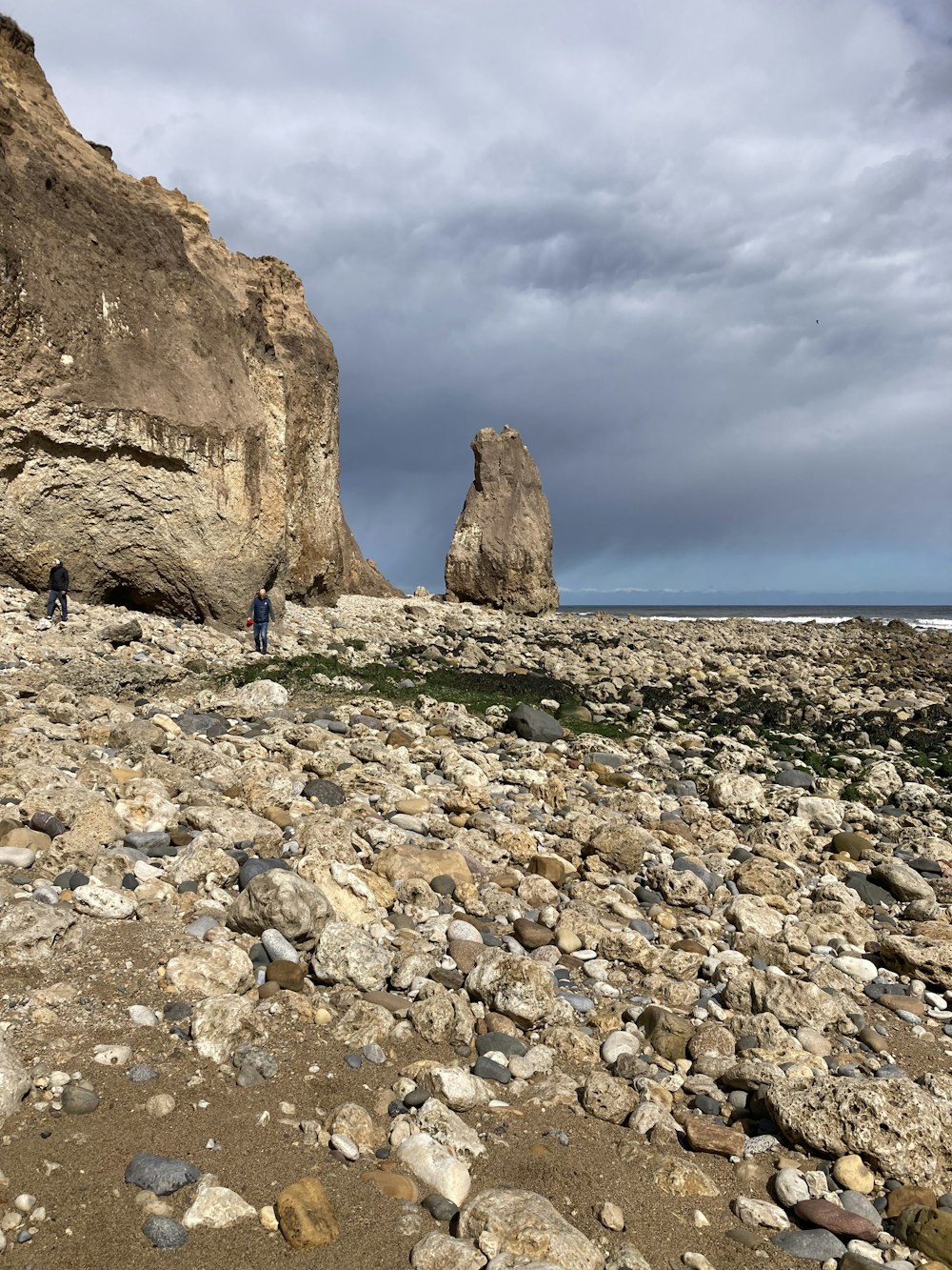 a couple of people standing on top of a rocky beach