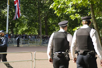 A British security officer attentively monitoring a busy UK event with a city skyline in the background.
