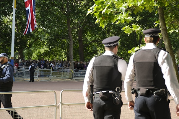 A British security officer attentively monitoring a busy UK event with a city skyline in the background.