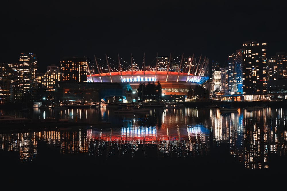 a city skyline at night with a lit up stadium