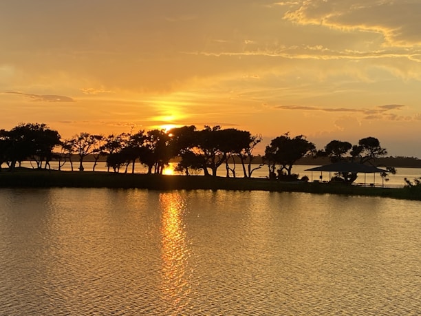 A vibrant sunset over Chilika Lake with the resort’s charming cottages in the foreground.