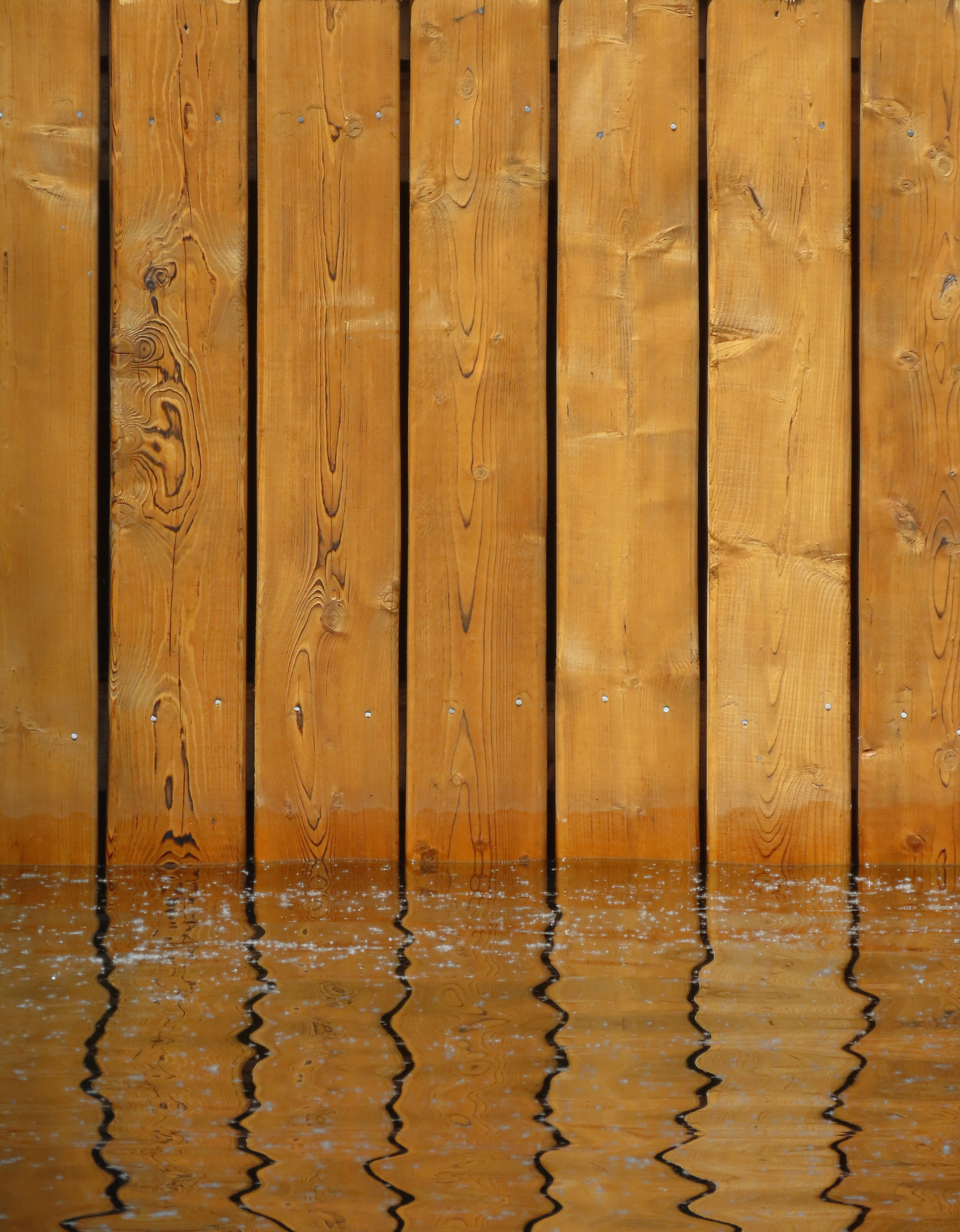 a wooden fence is reflected in the water