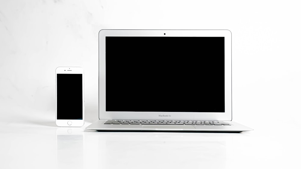 a white laptop computer sitting next to a cell phone