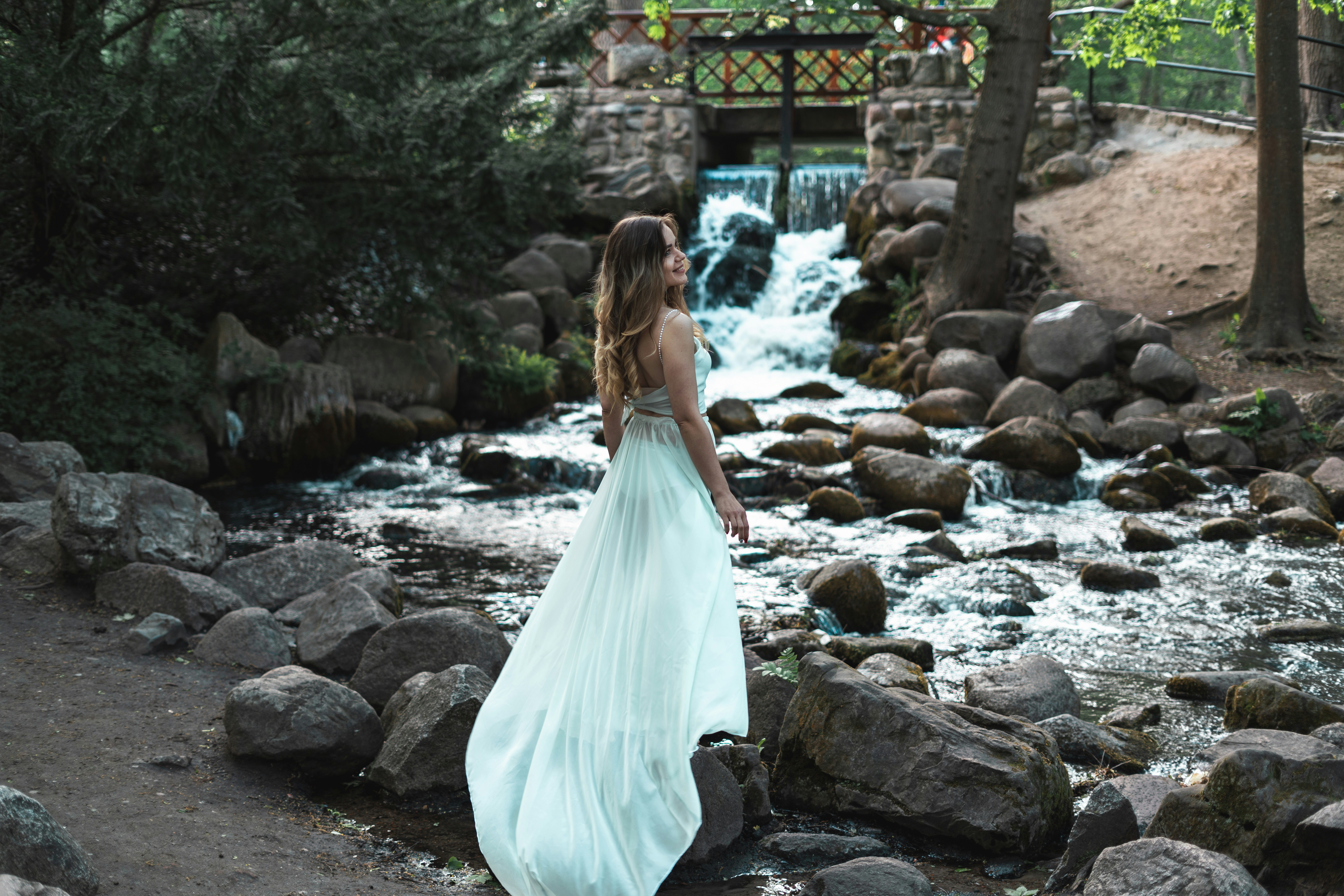 A woman in a blue dress is standing by a waterfall photo – Free Woman ...