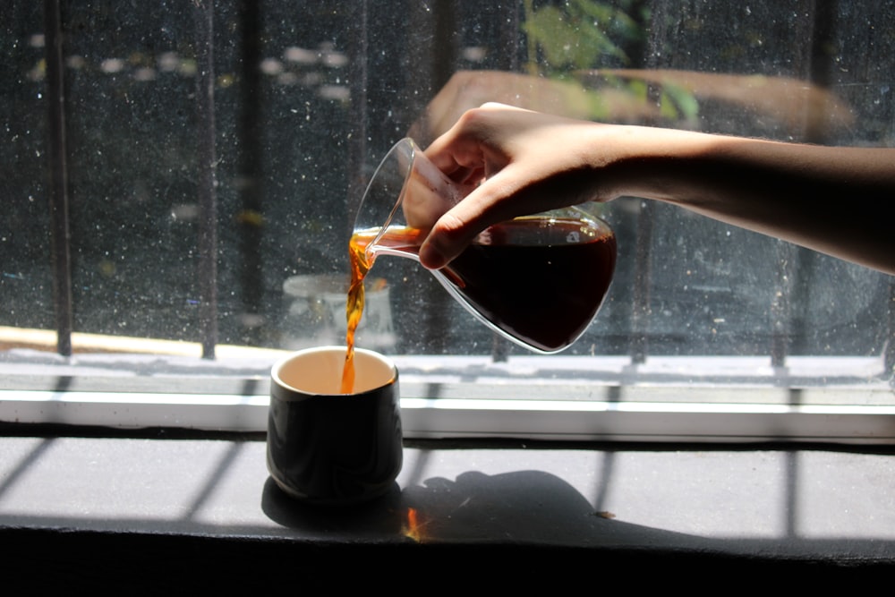 a person pours coffee into a cup