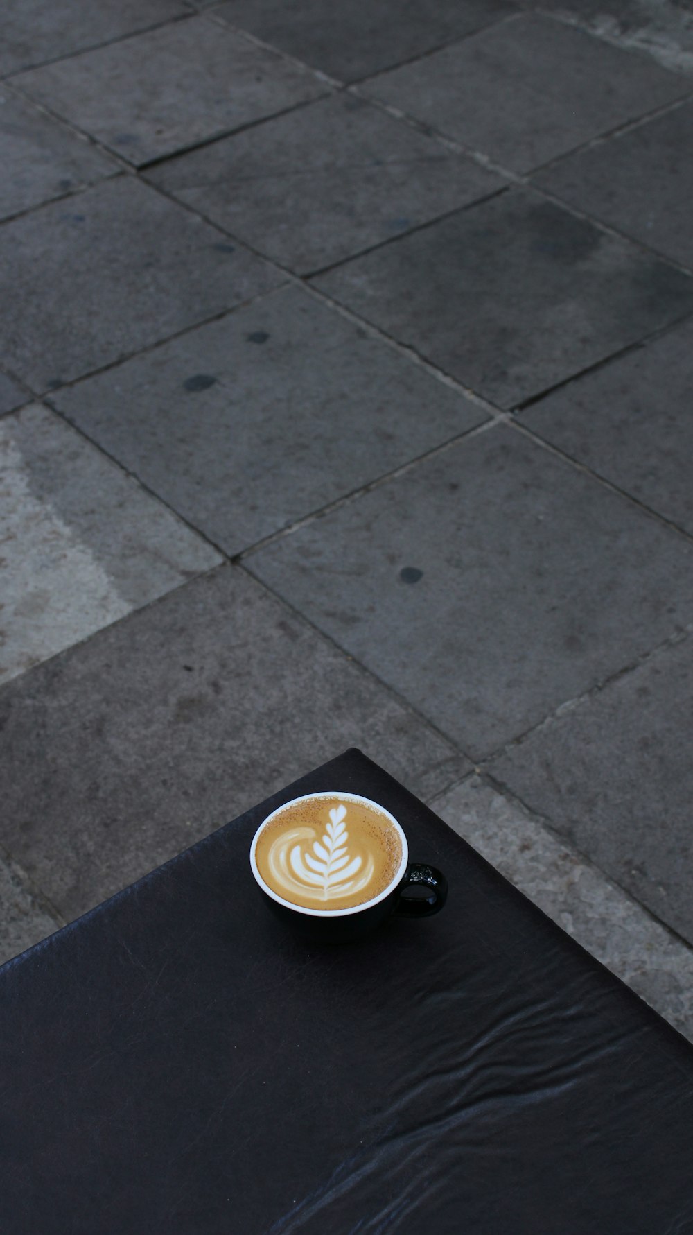 a cup of coffee sitting on top of a black table