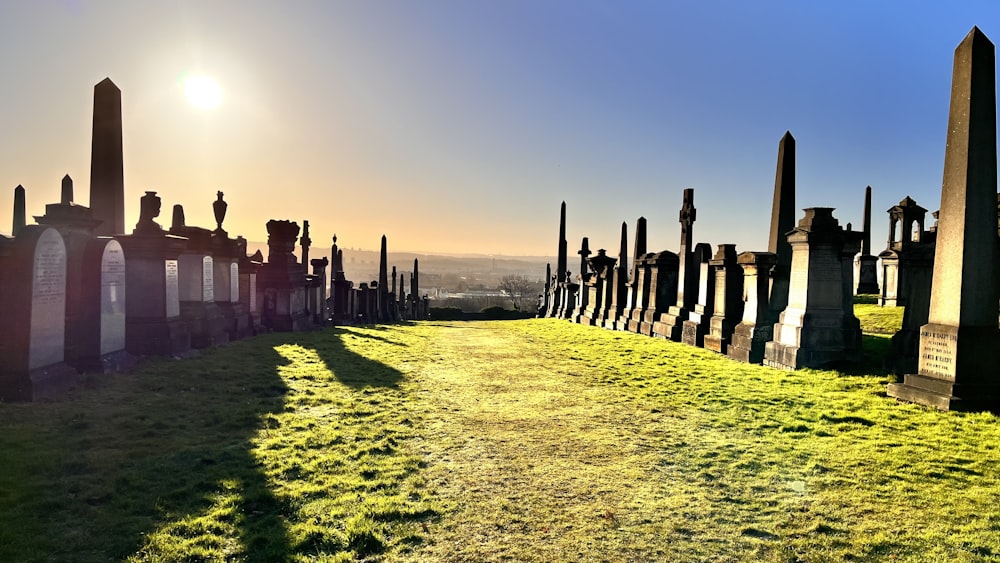 a row of headstones in a cemetery with the sun in the background