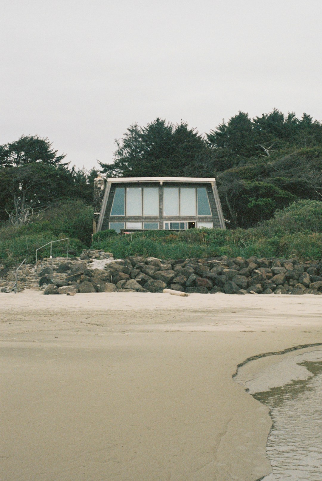 a house sitting on top of a hill next to a beach