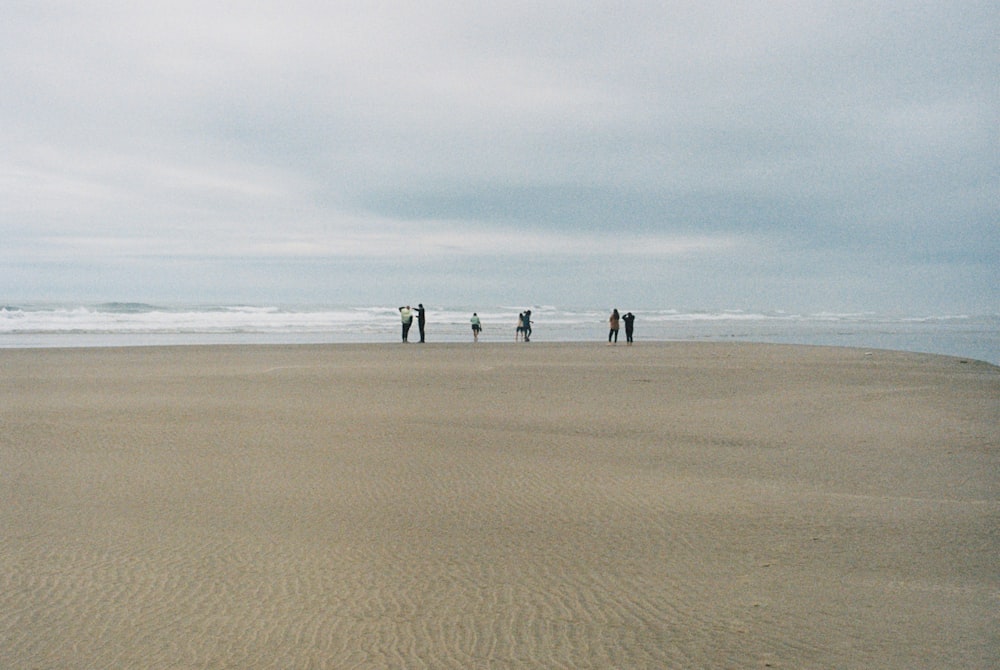 a group of people standing on top of a sandy beach