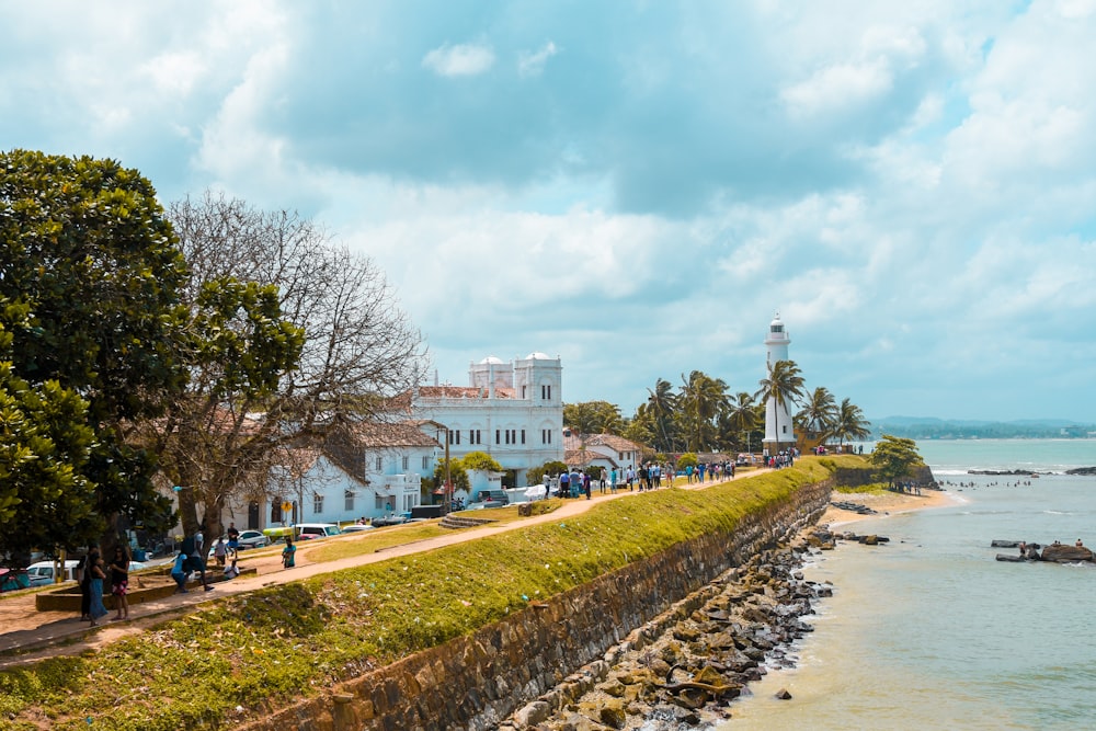 a group of people walking on a sidewalk next to a body of water