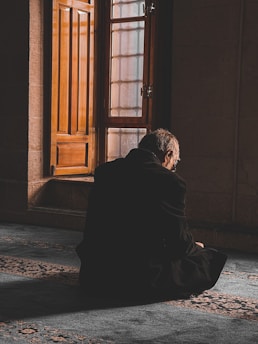 A thoughtful person listening intently in a quiet room filled with soft natural light.