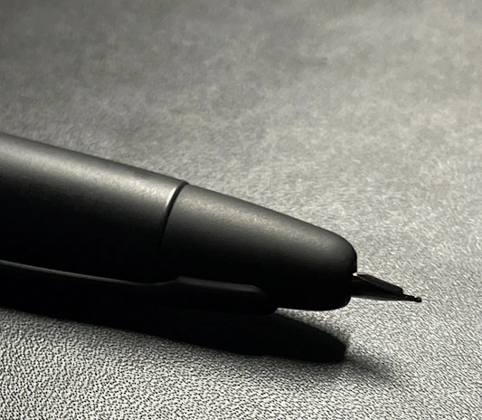 Close-up of the contrast between smooth polished wood and the delicate metal of the pen's tip.