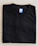 Close-up of a black 43 d'etat t-shirt folded neatly on a wooden table.