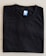A neatly folded black T-shirt with a blue size label marked XL on a light-colored surface.