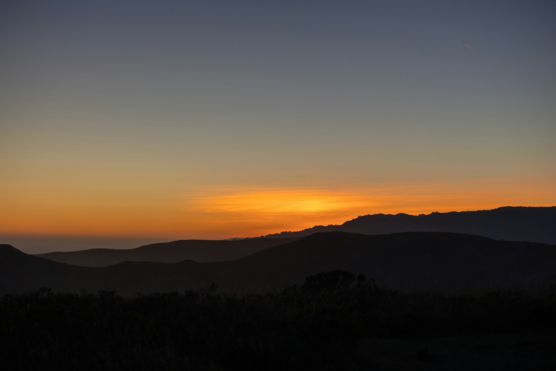 the sun is setting over a mountain range