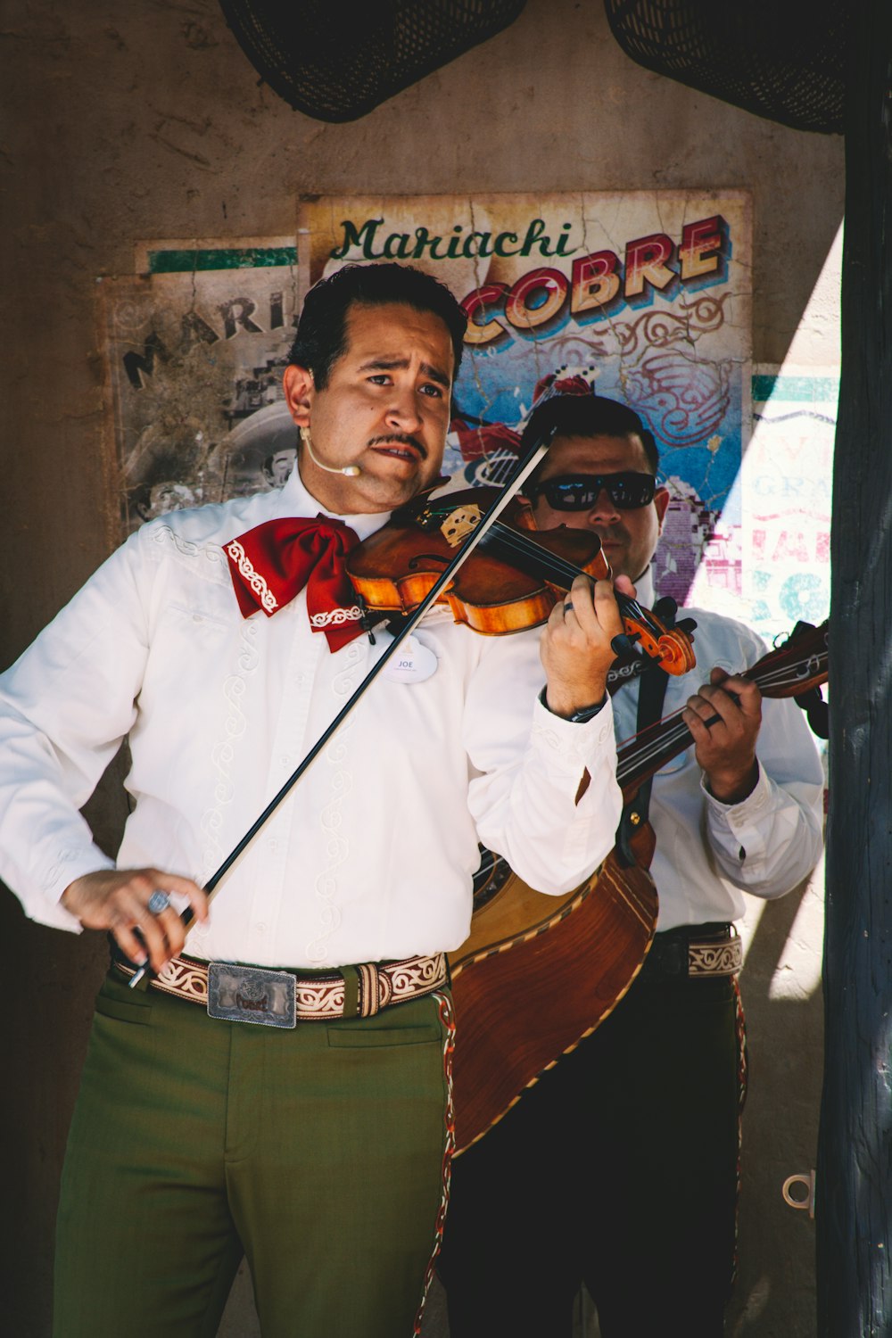 a man playing a violin with another man standing behind him