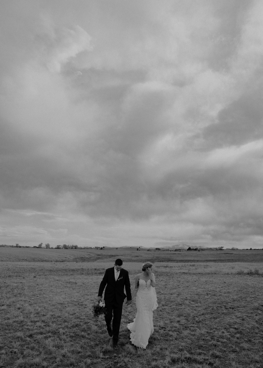 a bride and groom walking through a field