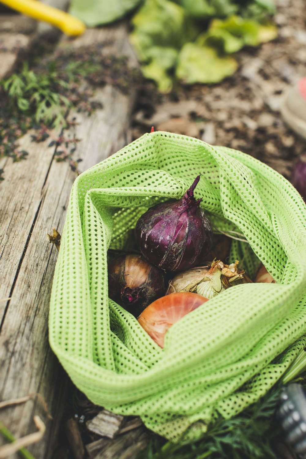 a green mesh bag filled with vegetables on top of a wooden table