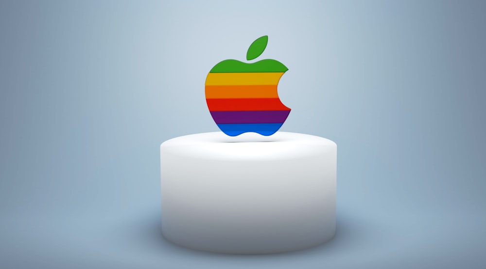 uma maçã arco-íris sentada em cima de um bolo branco