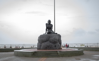 a statue of a woman sitting on top of a rock