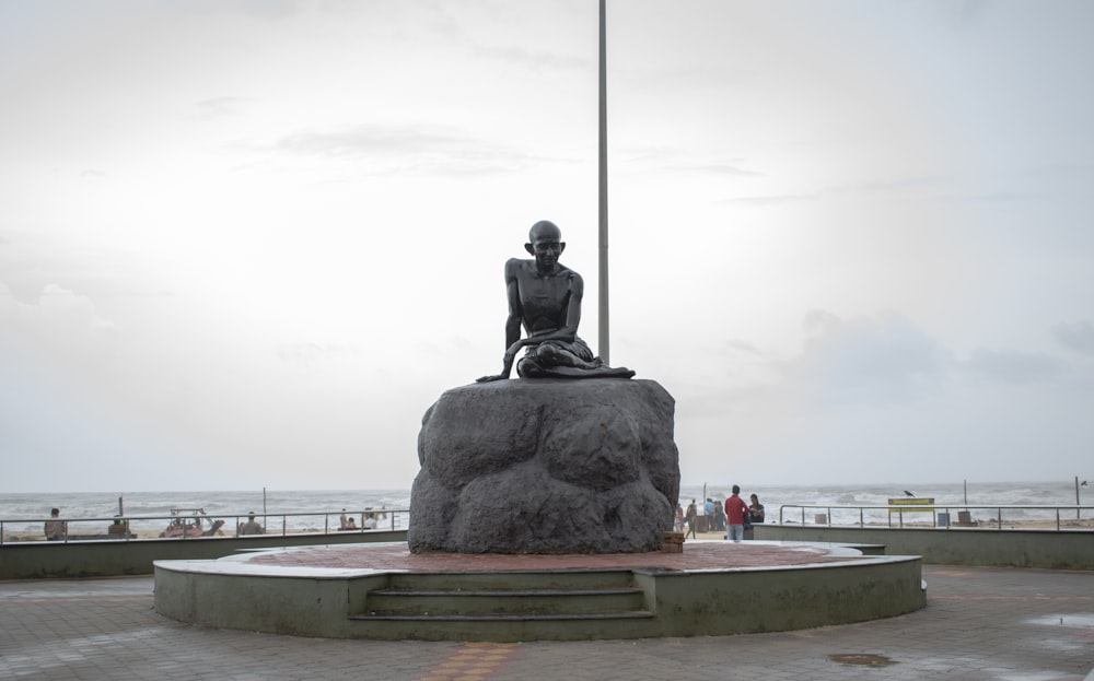 a statue of a woman sitting on top of a rock