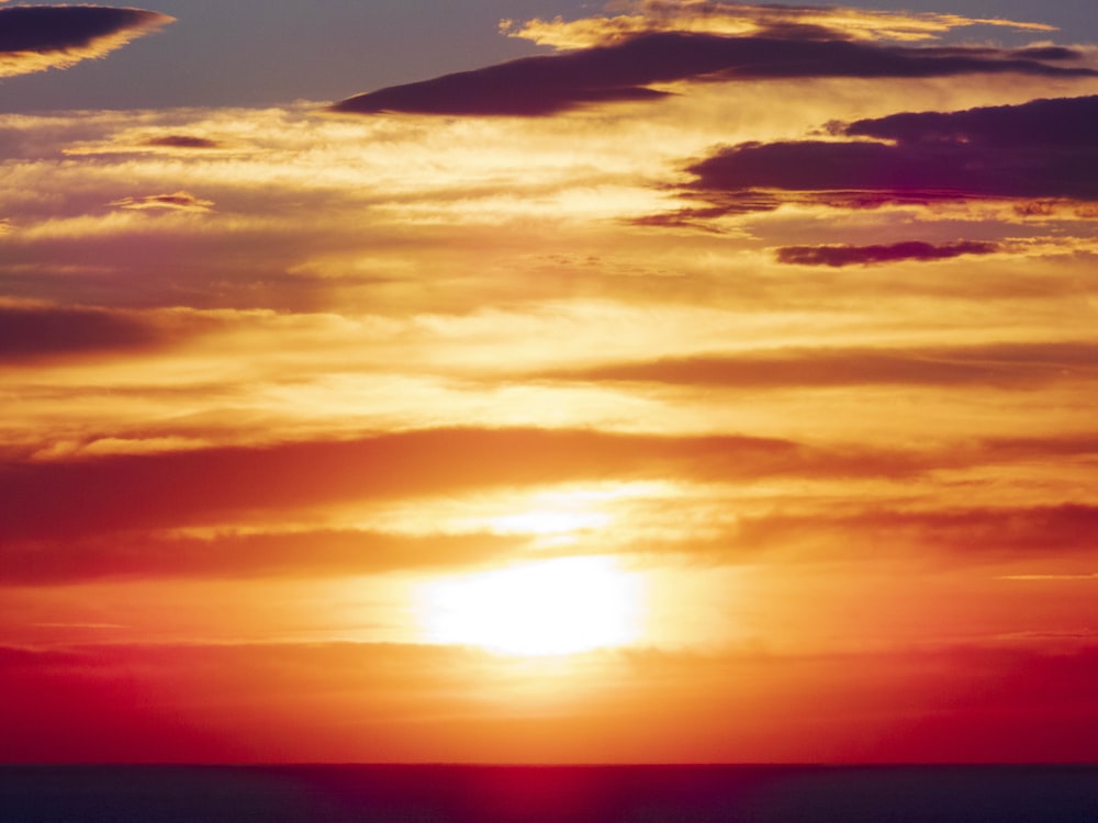 a plane flying in the sky at sunset